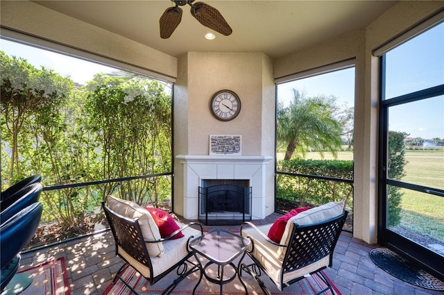 sunroom / solarium with ceiling fan and a tile fireplace