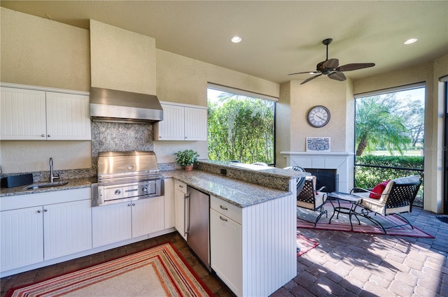 kitchen with refrigerator, kitchen peninsula, white cabinets, and sink