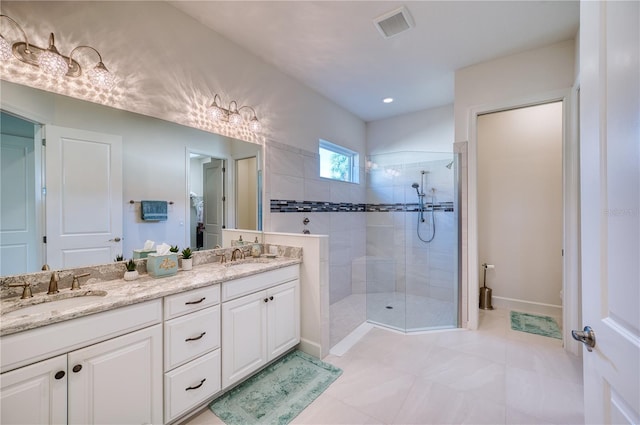 bathroom featuring a tile shower, tile patterned floors, and vanity