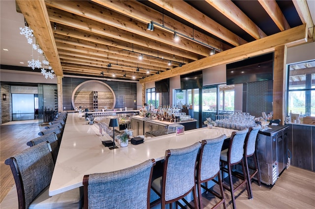 dining area with bar, rail lighting, light hardwood / wood-style floors, and a wealth of natural light