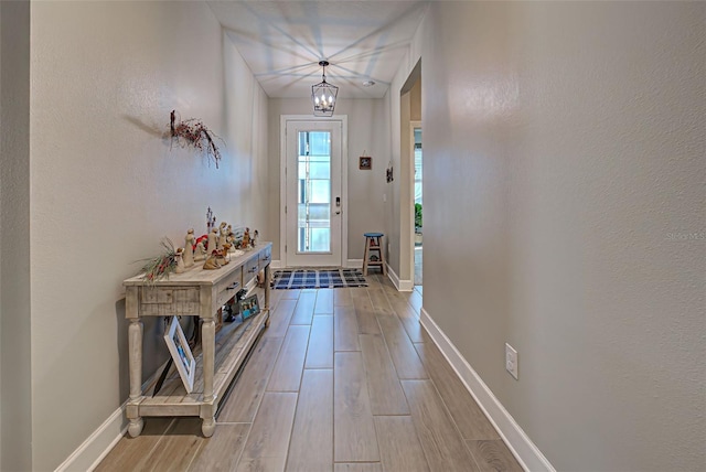 doorway to outside with an inviting chandelier and light wood-type flooring