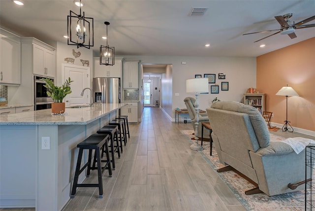 kitchen featuring white cabinets, a spacious island, decorative light fixtures, a kitchen bar, and stainless steel appliances