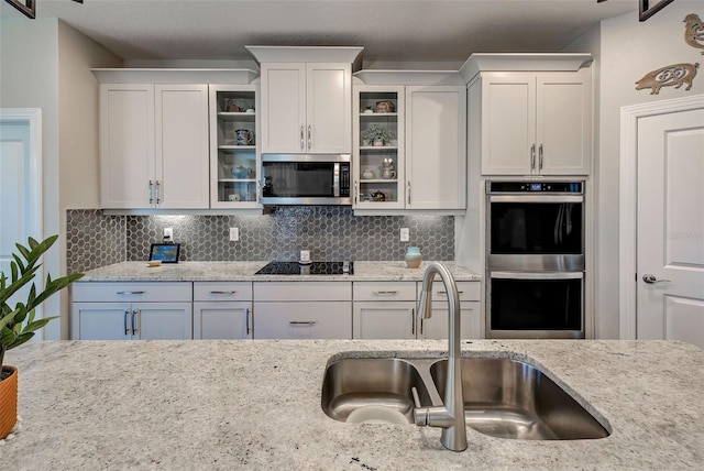 kitchen with white cabinets, stainless steel appliances, tasteful backsplash, and sink