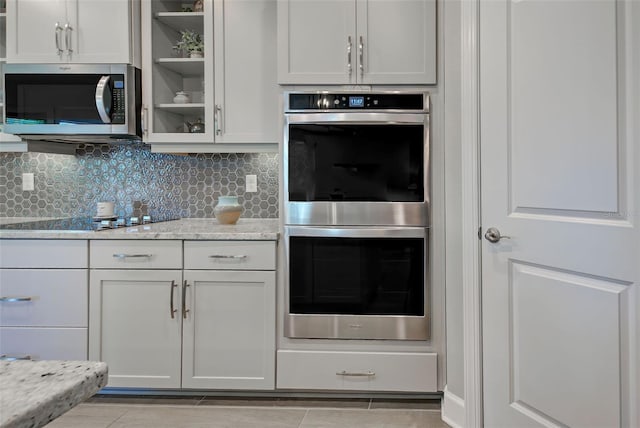 kitchen featuring white cabinets, appliances with stainless steel finishes, and light stone countertops