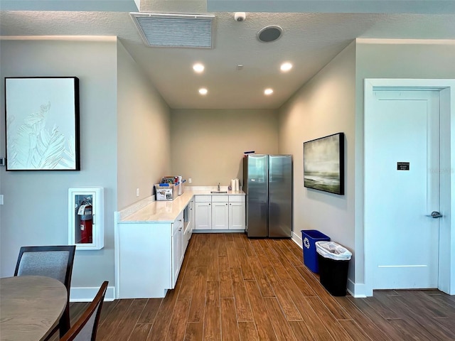 kitchen featuring stainless steel fridge, dark hardwood / wood-style flooring, white cabinetry, and sink