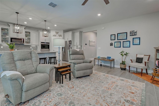 living room with light wood-type flooring, ceiling fan, and sink