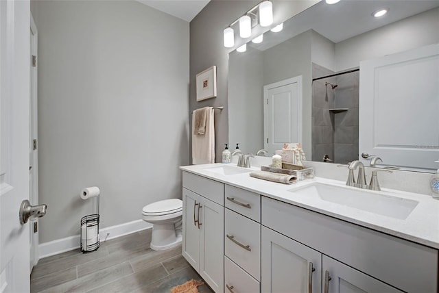 bathroom featuring hardwood / wood-style floors, vanity, toilet, and a tile shower