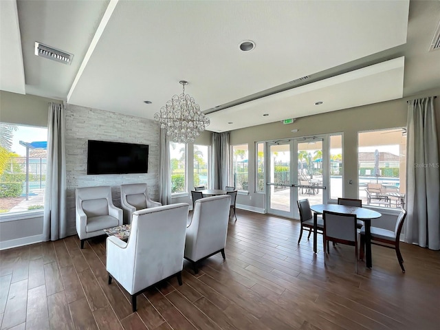 living room featuring a wealth of natural light, dark hardwood / wood-style floors, and an inviting chandelier