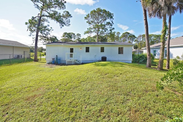 rear view of house with cooling unit and a lawn