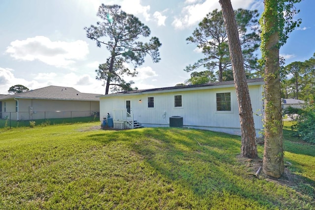 rear view of property featuring a lawn and central air condition unit