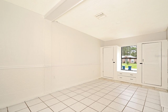 spare room featuring light tile patterned flooring and beam ceiling