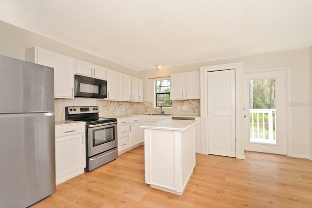 kitchen featuring a center island, backsplash, appliances with stainless steel finishes, white cabinets, and light wood-type flooring