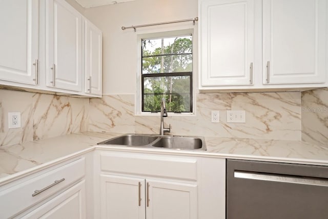 kitchen with backsplash, white cabinetry, stainless steel dishwasher, and sink