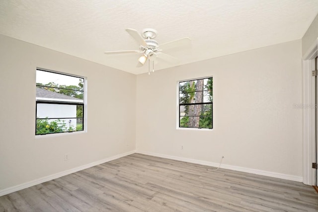 spare room with ceiling fan, light hardwood / wood-style floors, a textured ceiling, and a wealth of natural light