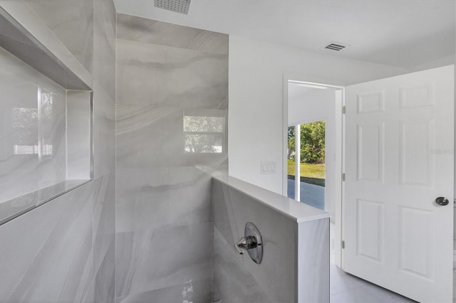 bathroom with a tile shower and tile patterned floors