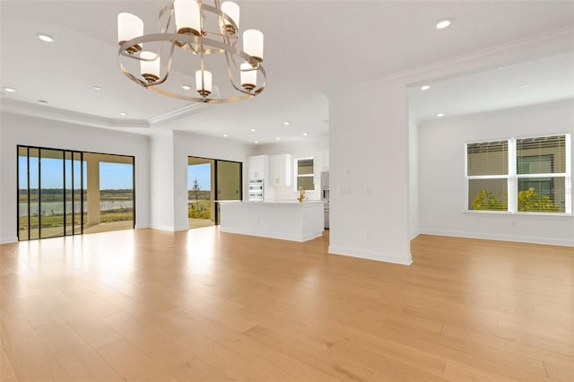 unfurnished living room featuring light hardwood / wood-style flooring, crown molding, and a notable chandelier