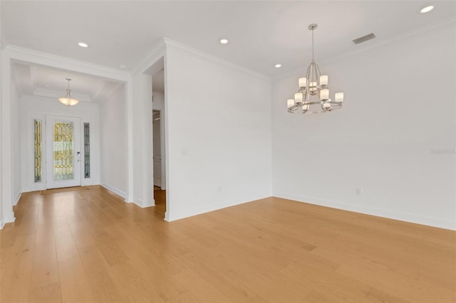 empty room with light wood-type flooring, a chandelier, and crown molding