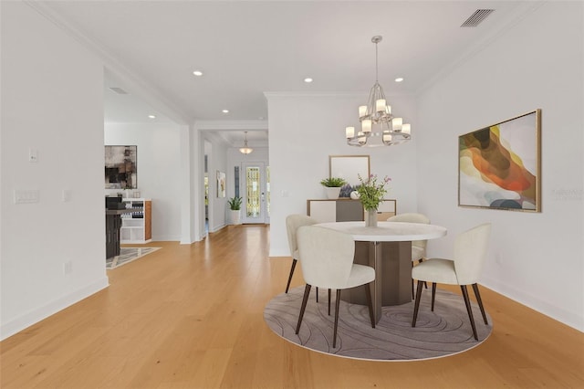 dining area featuring light hardwood / wood-style floors, crown molding, and a notable chandelier