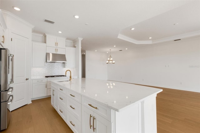 kitchen with decorative light fixtures, a spacious island, white cabinets, and light hardwood / wood-style flooring