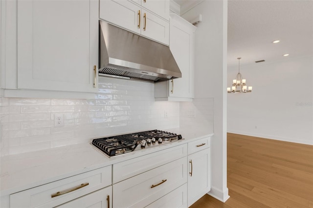 kitchen with decorative light fixtures, stainless steel gas stovetop, white cabinetry, light wood-type flooring, and ornamental molding