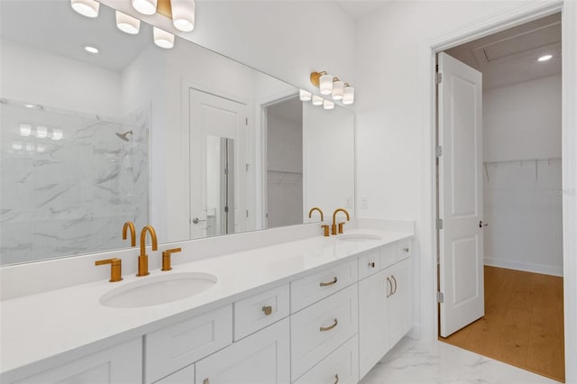 full bath with a sink, a marble finish shower, a spacious closet, and double vanity