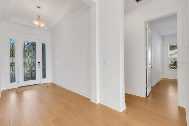 entrance foyer featuring baseboards, a raised ceiling, light wood-style flooring, and ornamental molding