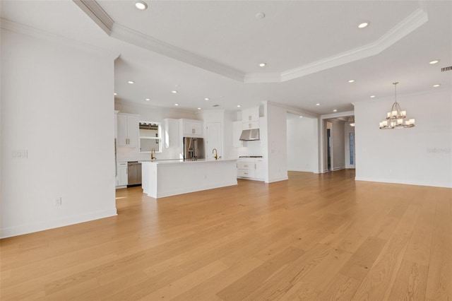 unfurnished living room featuring light wood finished floors, an inviting chandelier, recessed lighting, ornamental molding, and a raised ceiling