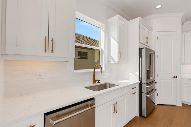 kitchen featuring crown molding, light wood-type flooring, appliances with stainless steel finishes, white cabinetry, and a sink