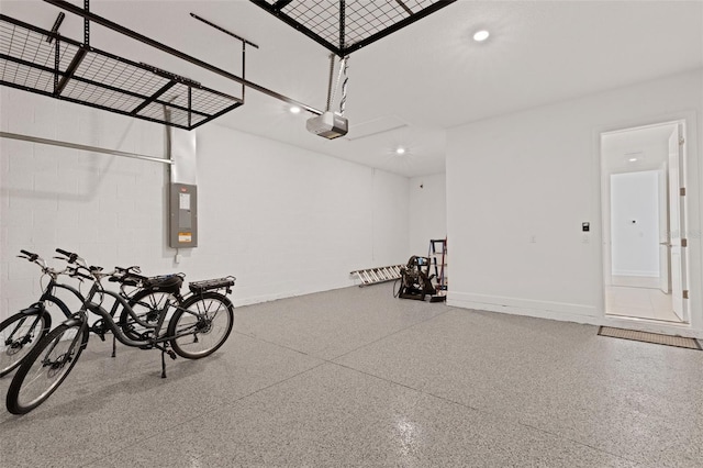 garage with concrete block wall, electric panel, a garage door opener, and recessed lighting