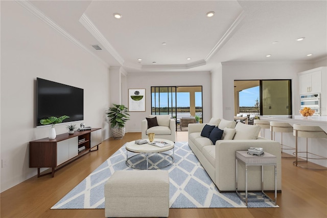 living room featuring visible vents, ornamental molding, wood finished floors, recessed lighting, and a raised ceiling