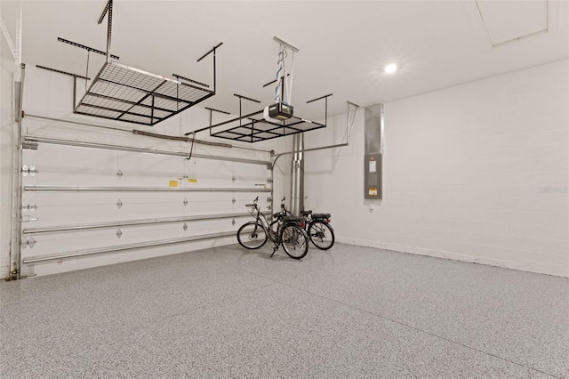 garage featuring electric panel, recessed lighting, concrete block wall, and a garage door opener