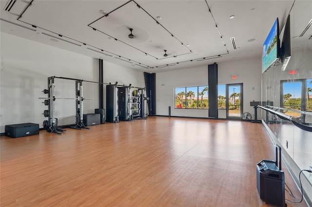 gym with light wood-style floors and a towering ceiling