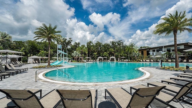 community pool featuring playground community, a water slide, and a patio area