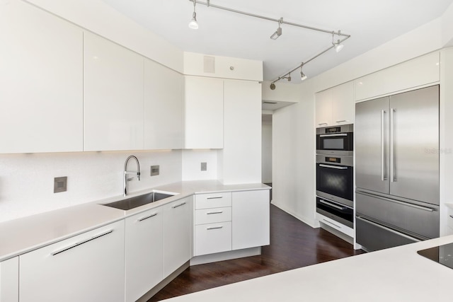 kitchen with tasteful backsplash, dark wood-type flooring, sink, stainless steel built in fridge, and white cabinets