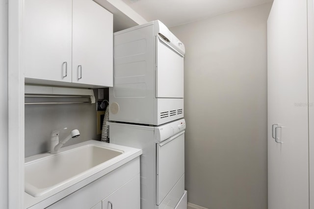 clothes washing area with cabinets, stacked washer and dryer, and sink