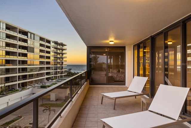 balcony at dusk featuring a water view