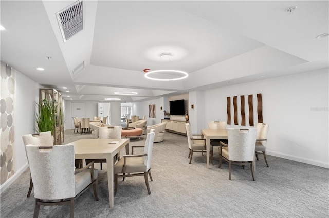 carpeted dining space with a tray ceiling