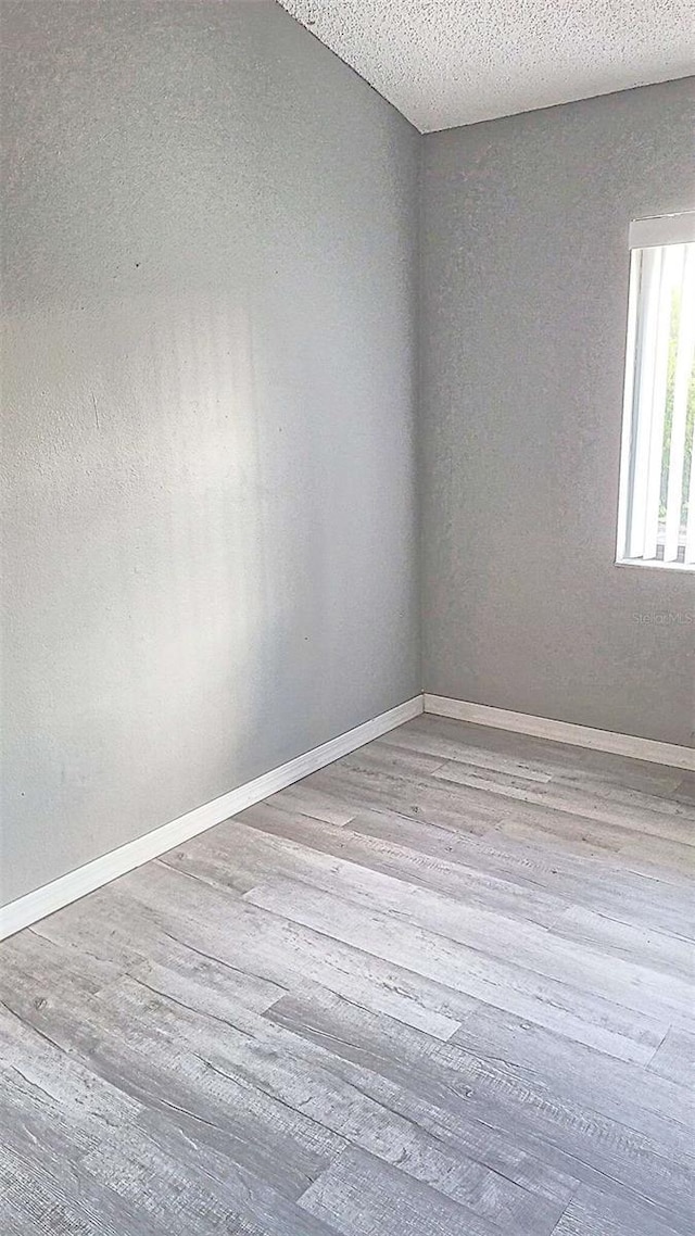 spare room featuring light hardwood / wood-style floors and a textured ceiling