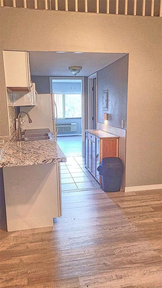 kitchen featuring light stone counters, sink, white refrigerator, light hardwood / wood-style flooring, and white cabinetry