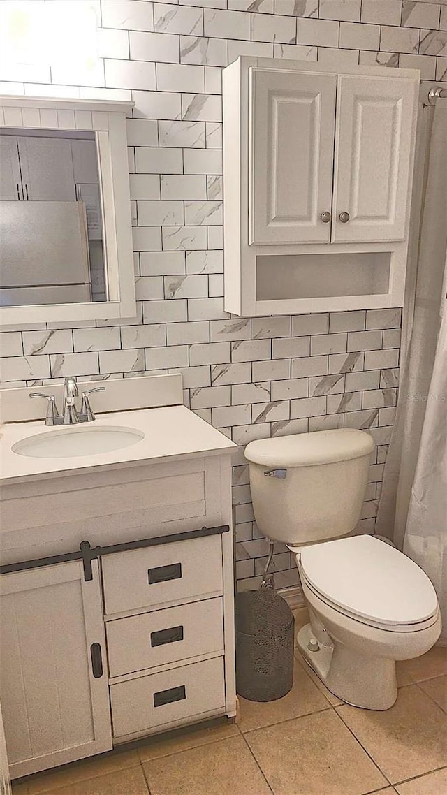 bathroom with tile patterned flooring, vanity, toilet, and tile walls