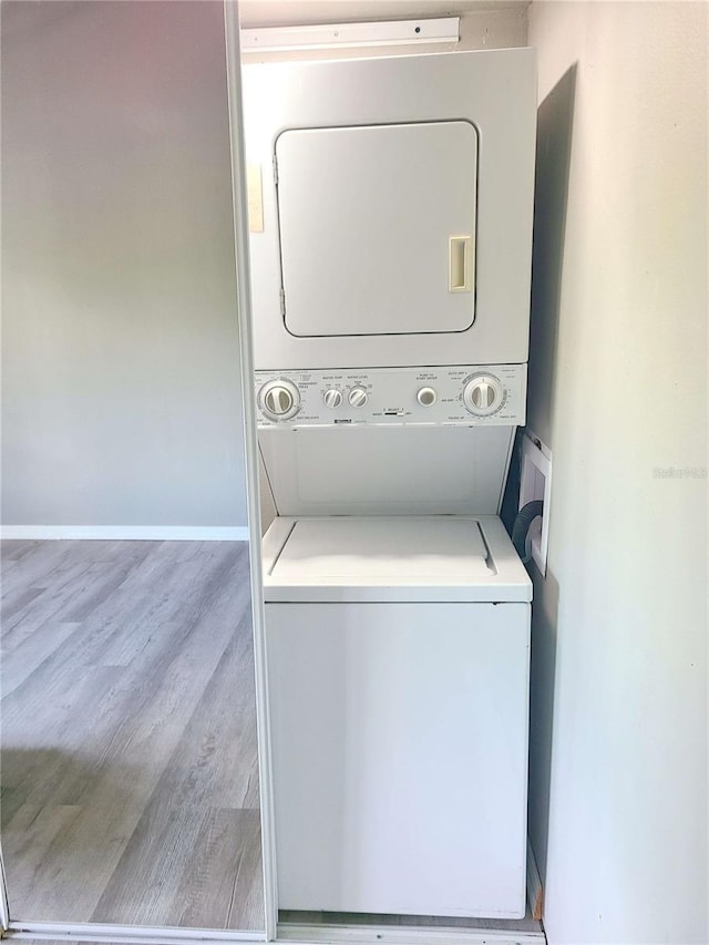 washroom with stacked washer and dryer and light hardwood / wood-style flooring