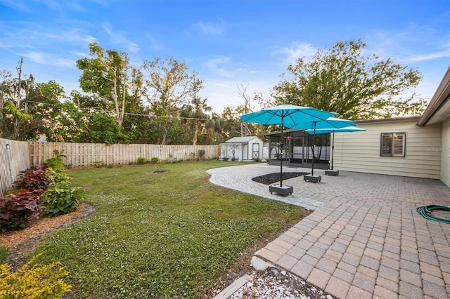 view of yard featuring a sunroom, an outdoor structure, and a patio