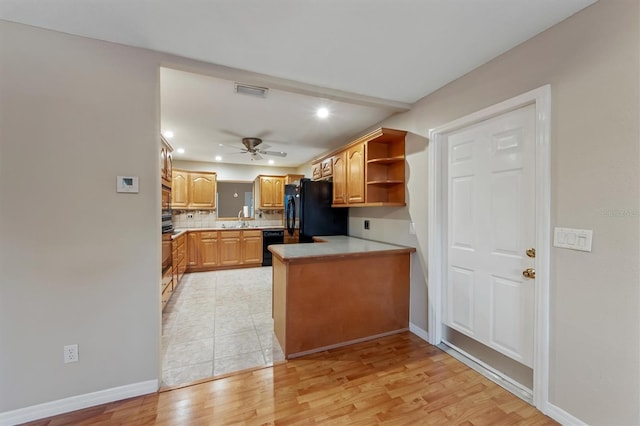 kitchen featuring kitchen peninsula, light wood-type flooring, tasteful backsplash, ceiling fan, and black appliances