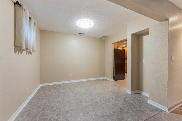 tiled empty room with a textured ceiling