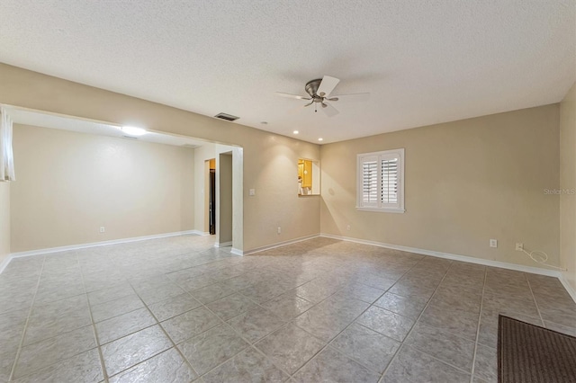 tiled empty room featuring a textured ceiling and ceiling fan