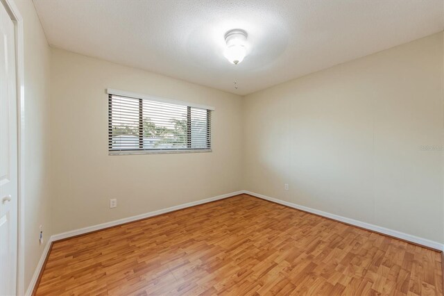 unfurnished room featuring a textured ceiling and light hardwood / wood-style flooring