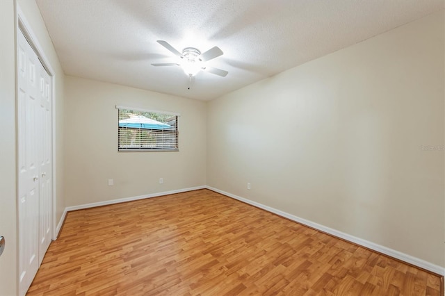 unfurnished bedroom with ceiling fan, a closet, light hardwood / wood-style floors, and a textured ceiling