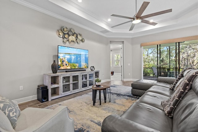 living room featuring a raised ceiling, crown molding, ceiling fan, and light hardwood / wood-style floors