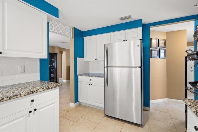 584 Beverly Rd, Venice, FL 34293 - kitchen with freestanding refrigerator, decorative backsplash, stone counters, and white cabinetry