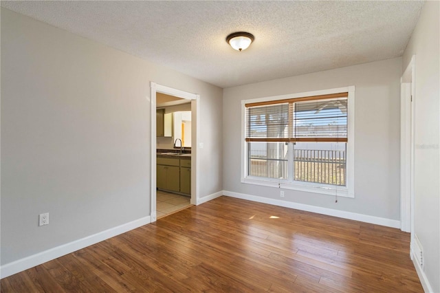 empty room with sink, wood-type flooring, and a textured ceiling